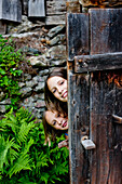 Two girls behind an old wooden door, Styria, Austria