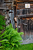 Zwei Mädchen verstecken sich hinter einer alten Holztür, Steiermark, Österreich