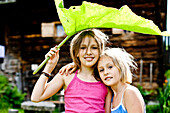 Two girls covering heads with a big leaf, Styria, Austria