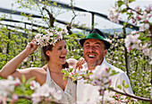 Young woman and fruit farmer between flowering apple trees, Riegersburg, Styria, Austria