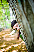 Junge Frau hinter einem Baum, Steiermark, Österreich