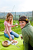 Two young women enjoying local specialties in a vineyard, Riegersburg, Styria, Austria