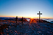 Two hikers at summit of Hochschwab mountain at sunrise, Hochschwab, Styria, Austria