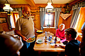 Mann serviert Paar Essen in einer Berghütte, Hochschwabgebiet, Steiermark, Österreich