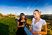 Zwei junge Frauen trinken Weißwein auf einem Weingut, Gamlitz, Steiermark, Österreich