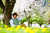Man sitting under flowering apple tree, Stubenberg, Styria, Austria