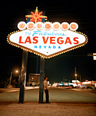 USA, Nevada, Las Vegas, young man standing under welcome sign of Las Vegas at night
