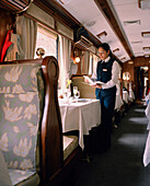 PERU, Cusco, South America, Latin America, waitress holding menu in Hiram Bingham train