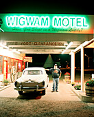 USA, Arizona, man standing by classic car at Wigwam motel