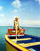 ARUBA, young woman in bikini relaxing on fishing boat, Surfside Beach, Oranjestad