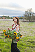 USA, California, Sonoma, Les Petit Maisons guest cottages and Market, owner Gayle Jenkins walks with freshly cut sunflowers