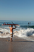 USA, California, Malibu, a paddleboarder watches his friends paddle out at Zuma Beach