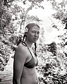 FIJI, Northern Lau Islands, a young woman stands on a path cut through a lush jungle (B&W)