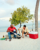 USA, Florida, friends having a beach BBQ, cooking fish, Islamorada