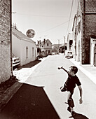 FRANCE, Burgundy, boy playing with soccer ball in street, Buffon (B&W)