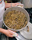 GREECE, Patmos, Skala, Dodecanese Island, Irini Kaneli holds a pot full of dolmades in the kitchen of Taverna Tzivaeri
