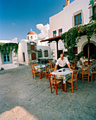 GREECE, Patmos, Chora, Dodecanese Island, a man sets tables at a restaurant in the island top village of Chora