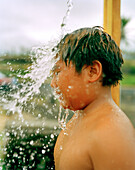 USA, Hawaii, The Big Island, close-up of a young boy under an outdoor shower