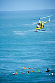 USA, Hawaii, Oahu, helicopter above surfers in the ocean at Waimea bay