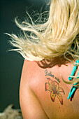USA, Hawaii, Oahu, rear view of woman with a flower tattoo on her back