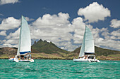 MAURITIUS, Trou D'eau Deuce, tourists sail in the Indian Ocean off the East coast of Mauritius with the 4 Sisters Mountains in the background