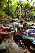 MAURITIUS, Bois Cherie, Mutty Megah (age 63) washes her clothes in a small stream behind her home