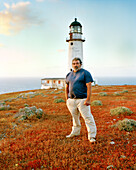 MEXICO, Baja, portrait of lighthouse keeper standing in front of lighthouse, San Benitos Islands