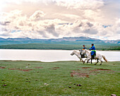 MONGOLIA, Khuvsgul National Park, Nomadic horsemen run their horses along Toilogt Lake