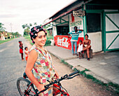 PANAMA, Bocas del Toro, a young woman hangs out on the street in front of her house with a head of hair full of curlers, Central America
