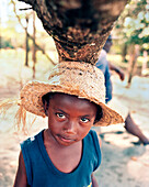 PANAMA, Bocas del Toro, a young boy Tapio finds shade under a fallen tree trunk, Central America