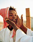 SAUDI ARABIA, human hands touching an Egyptian boy's face, Camel Market