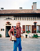 SWITZERLAND, Motiers, George Montandon stands in front of his home holding a cow bell that was given to him by a friend for his 45th wedding anniversary, Jura Region
