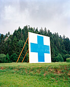 SWITZERLAND, Motiers, the symbol of the Swiss is displayed on the hillside above the town of Motiers, Jura Region