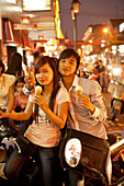 VIETNAM, Hanoi, a sweet young couple sits on their moped eating ice cream on a hot Summer night in downtown Hanoi