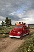 USA, Wyoming, Encampment, kids ride an old restored firetruck to a dinner cookout, Abara Ranch