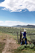 USA, Wyoming, Encampment, cowgirl closes a barbwire fence, Big Creek Ranch