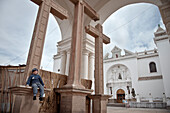 Young boy sitting at a cross in front of Basilica of dark virgin, Virgen Morena, Copacabana, lake Titicaca, Bolivia, Andes, South America