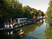 Stand up paddling on a canal in front of house boats, Hanseatic City of Hamburg, Germany