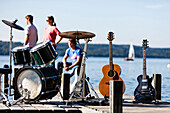 Musical instruments on a jetty at lake Starnberg, three persons in background, Bavaria, Germany