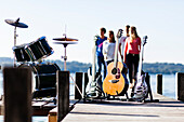 Musical instruments on a jetty at lake Starnberg, four persons in background, Bavaria, Germany