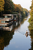 Couple canoeing on Eilbek canal, houseboats in background, Hamburg, Germany