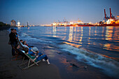 Guests on the beach near Cafe Strandperle in Hamburg-Oevelgoenne, the HHLA container terminal is situated on the opposite bank of the Elbe, Hamburg harbour, Hamburg, Germany