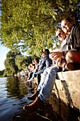 People sitting on the seawall at Alsterperle Cafe and bar, Eduard-Rhein-Ufer 1, Outer Alster Lake, Hamburg, Germany