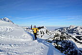 Frau auf Skitour steigt zu Großer Traithen auf, Wendelstein im Hintergrund, Mangfallgebirge, Bayerische Alpen, Oberbayern, Bayern, Deutschland