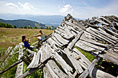 Two female hikers resting near the remains of a wooden lodge, Nockberge, Carinthia, Austria