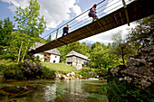 Two female hikers passing a swing bridge, Alpe-Adria-Trail, Trenta,  Slovenia