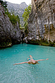 Junge Frau badet im Flusses Soca, Alpe-Adria-Trail, Tolmin, Slowenien