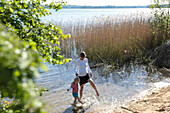 Mother and son standing in lake Carwitz, Conow, Feldberger Seenlandschaft, Mecklenburg-Western Pomerania, Germany