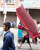 Nepal, City of Katmandu, man wearing 32 armchairs //Nepal, ville de Kathmandou, homme portant 32 fauteuils.