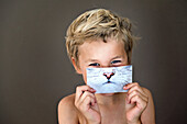 Boy holding picture of cat over face